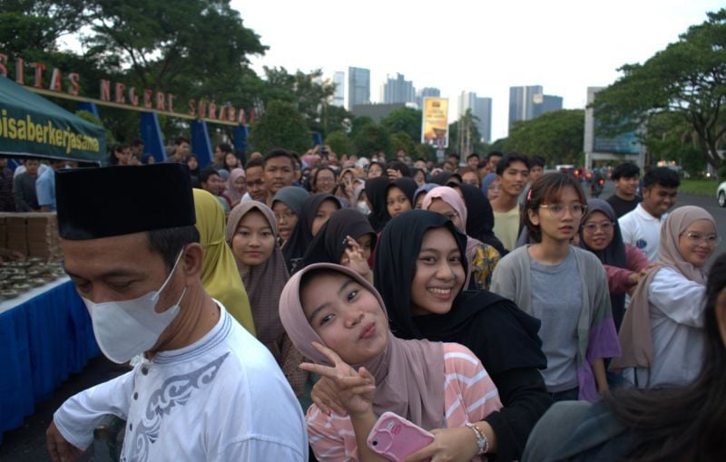 Mahasiswa Universitas Negeri Surabaya dan masyarakat sekitar antre takjil untuk buka bersama di halaman depan gerbang utama UNESA 