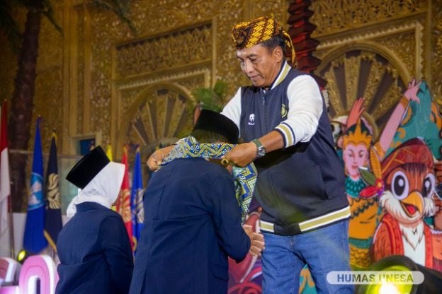 Rektor UNESA mengenakan almamater dan shal atau selendang kepada dua perwakilan mahasiswa baru UNESA, simbol pengukuhan.